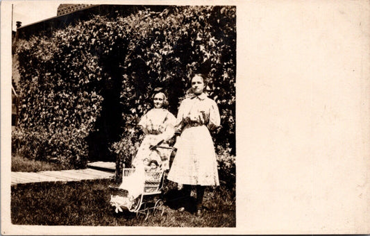 Real Photo Postcard Two Girls with Dolls in Baby Stroller Carriage in Garden